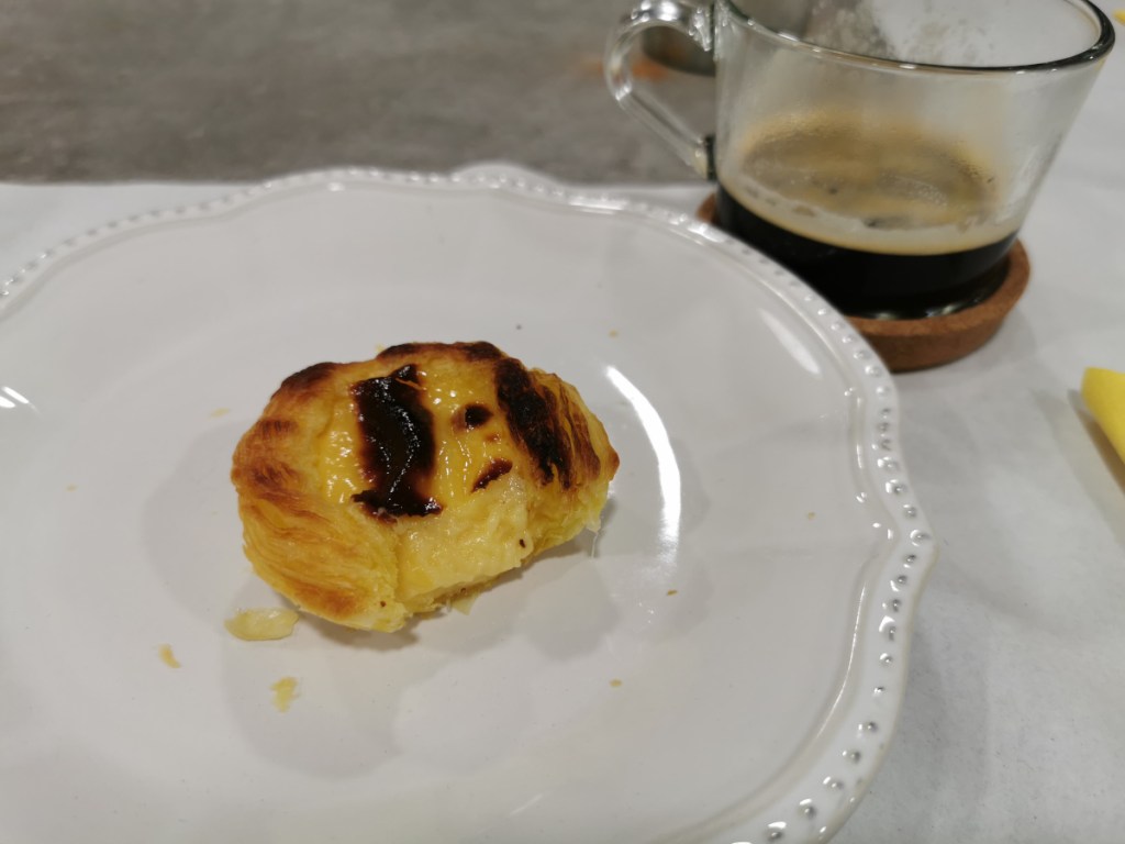 Pastel de nata con un mordizco y un cafe espresso